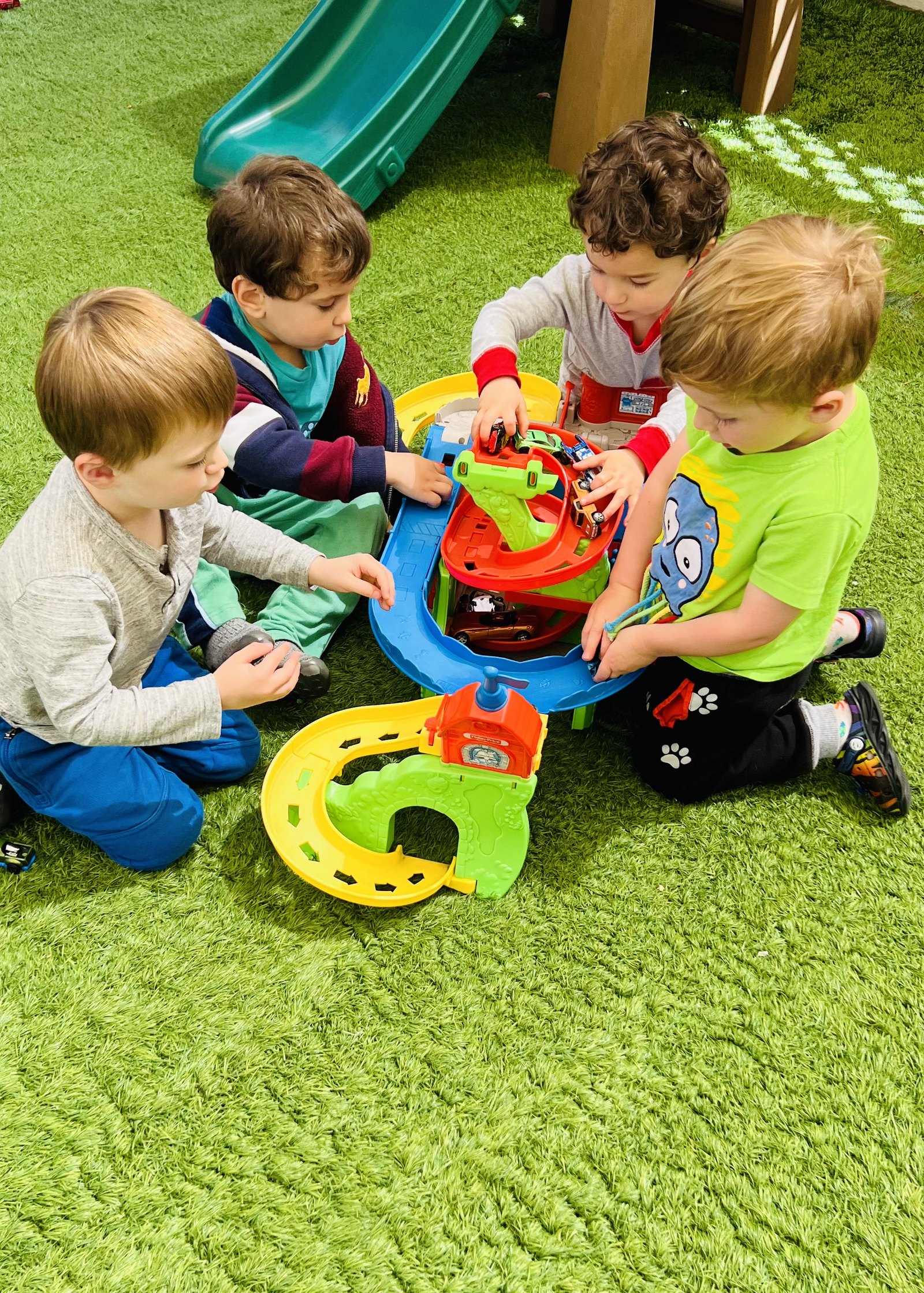 Children playing together with toys on indoor grass